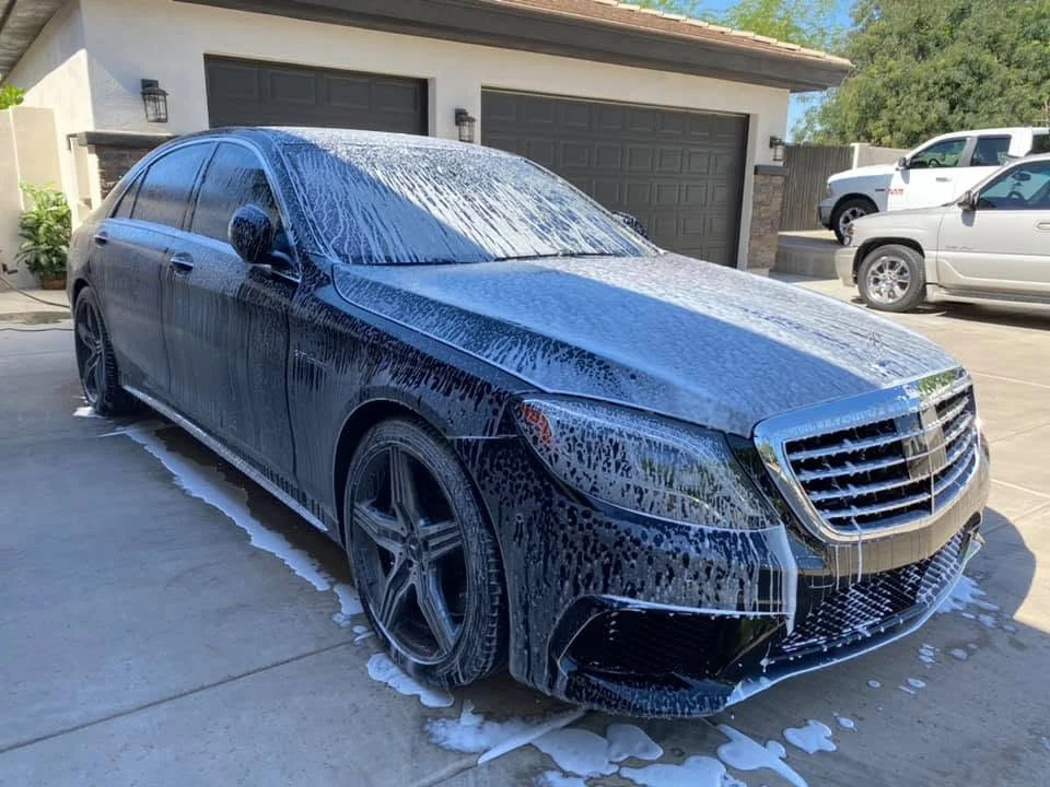 A sedan being washed outside a garage